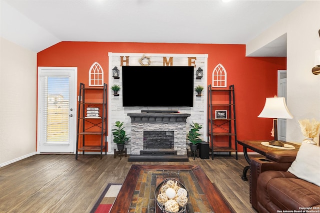 living room with baseboards, lofted ceiling, wood finished floors, and a stone fireplace