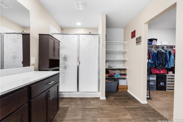 bathroom with vanity, a shower stall, wood finished floors, a spacious closet, and baseboards