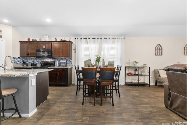 kitchen featuring dark wood-style flooring, stainless steel electric range oven, a sink, black microwave, and open floor plan
