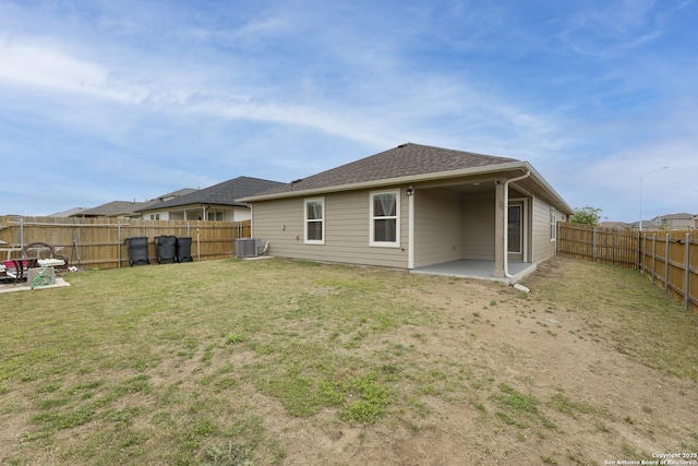 rear view of property with a fenced backyard, a lawn, central air condition unit, and a patio