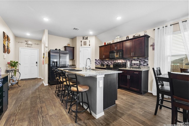 kitchen with dark wood-type flooring, appliances with stainless steel finishes, a breakfast bar, and visible vents