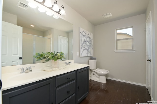 bathroom with toilet, a sink, wood finished floors, and visible vents