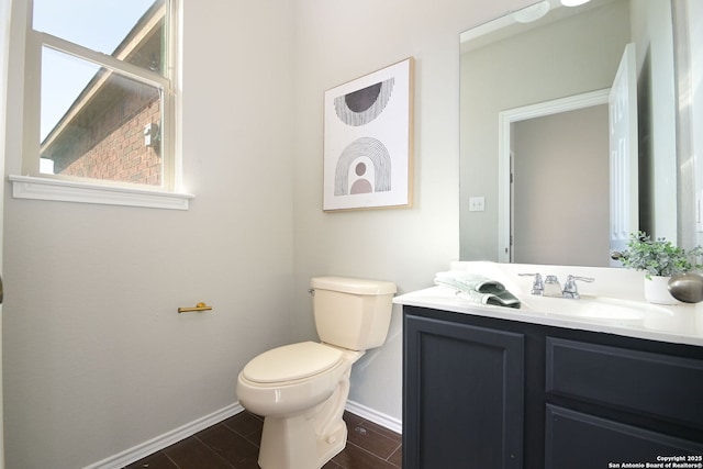 half bath featuring baseboards, toilet, and vanity