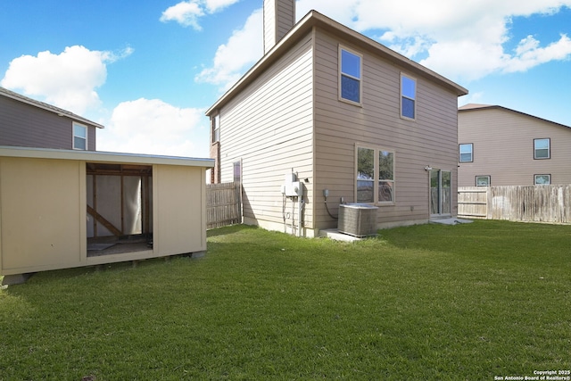 back of property with a lawn, fence, and central AC