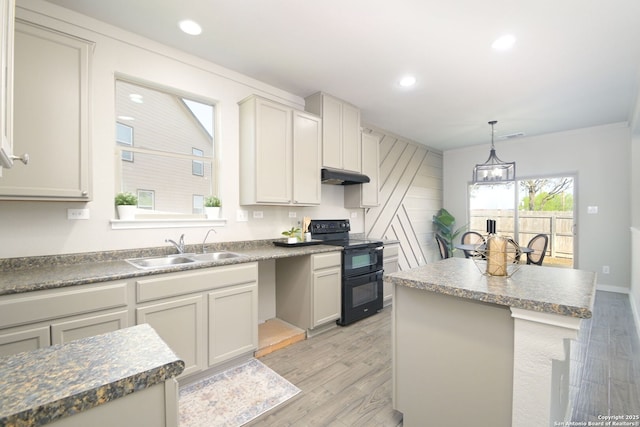kitchen with range with two ovens, a sink, under cabinet range hood, and light wood-type flooring