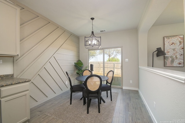 dining area with an inviting chandelier, wood finished floors, baseboards, and visible vents