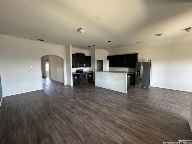 unfurnished living room featuring baseboards, visible vents, arched walkways, and dark wood-type flooring