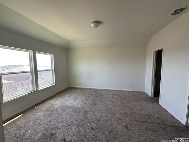 carpeted spare room featuring baseboards, lofted ceiling, and visible vents