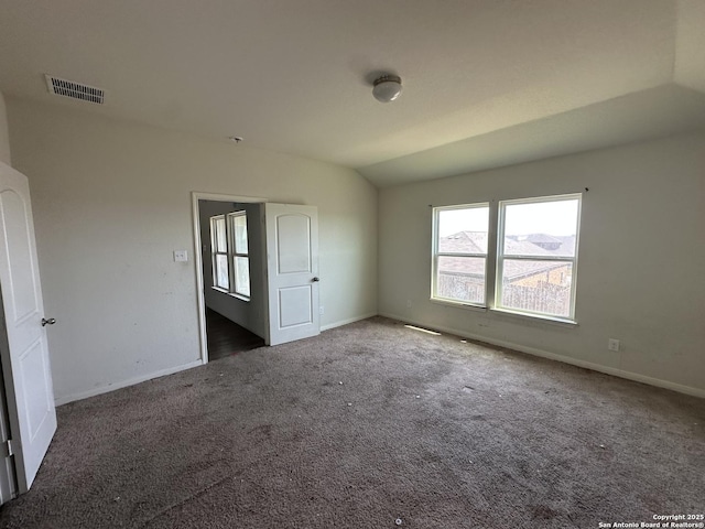spare room featuring baseboards, visible vents, carpet, and vaulted ceiling