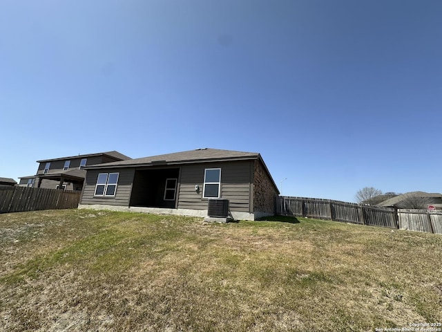back of property with cooling unit, fence, and a lawn