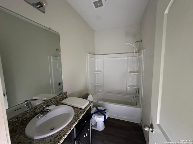 full bath featuring visible vents, toilet, wood finished floors, vanity, and shower / bath combination