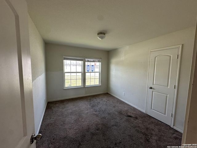 carpeted spare room featuring baseboards