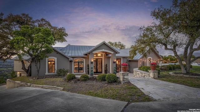 2471 Village Oak, Canyon Lake, TX 78133 - view of front of house with metal roof, an attached garage, stucco siding, a standing seam roof, and driveway