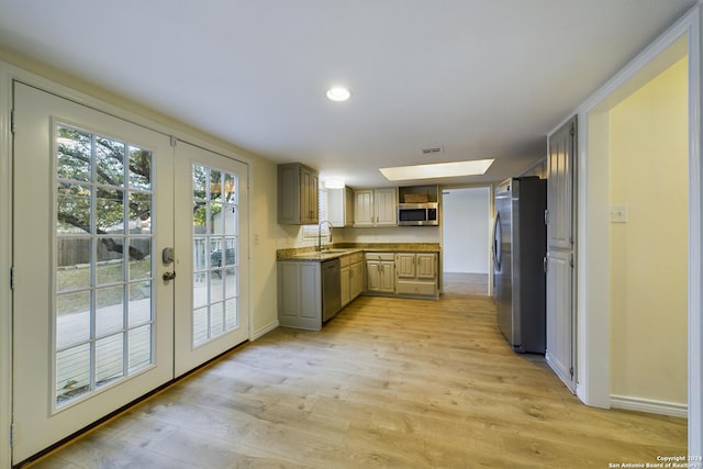 kitchen with a sink, french doors, light wood-style flooring, and stainless steel appliances