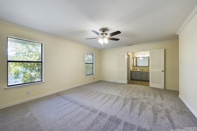unfurnished bedroom featuring crown molding, carpet, baseboards, ensuite bath, and a ceiling fan