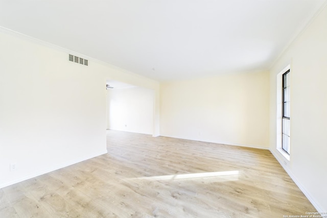 unfurnished room featuring baseboards, visible vents, crown molding, and wood finished floors
