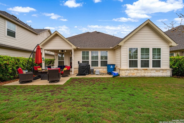 rear view of house featuring an outdoor living space, a lawn, a patio area, a shingled roof, and stone siding