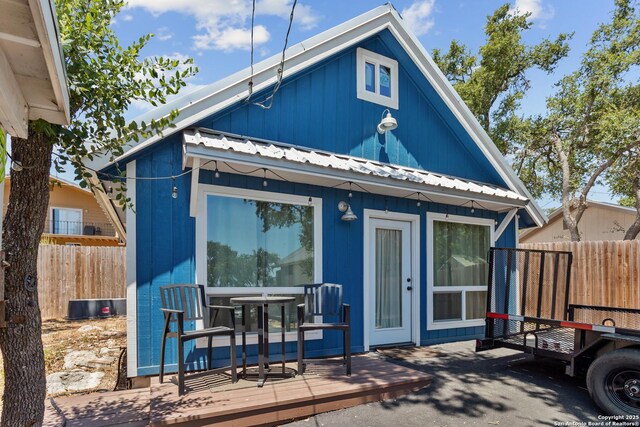 back of property with metal roof, a deck, and fence