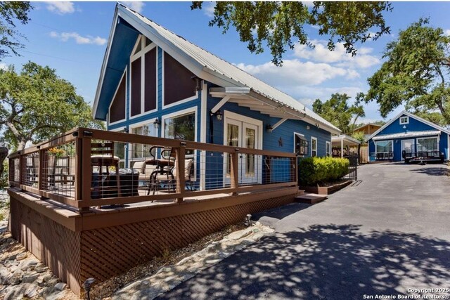 view of side of property featuring metal roof, a wooden deck, and french doors