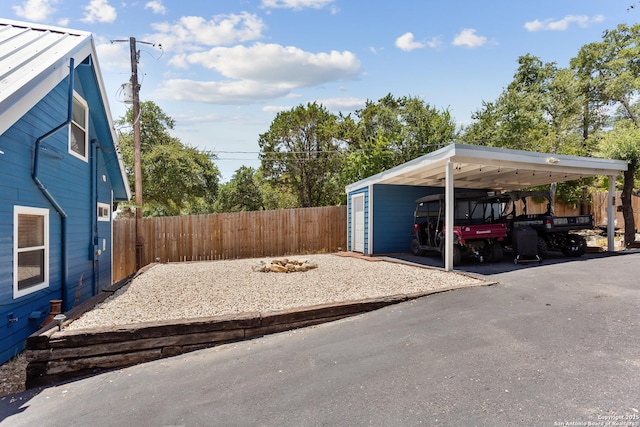 view of yard with driveway, fence, and a carport