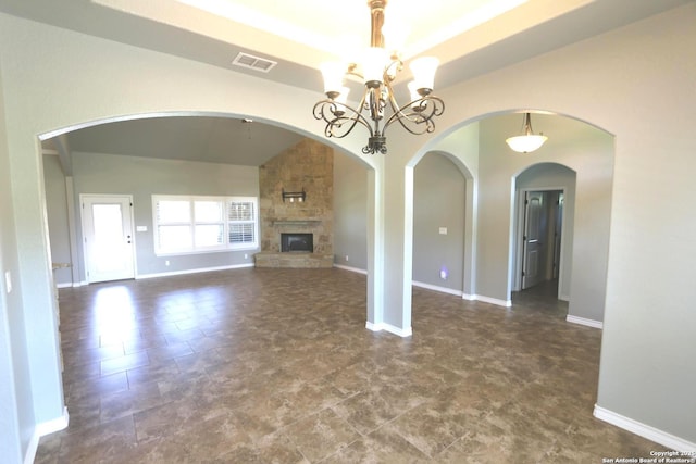 unfurnished living room featuring baseboards, a stone fireplace, a chandelier, and visible vents
