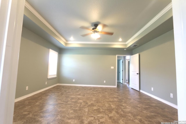 spare room featuring baseboards, a ceiling fan, a tray ceiling, and ornamental molding