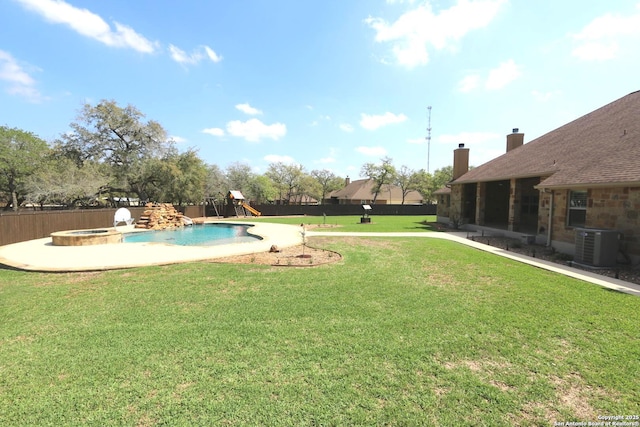 view of swimming pool with a lawn, a pool with connected hot tub, central AC unit, fence, and a playground