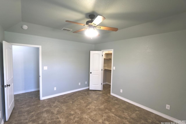 unfurnished bedroom featuring ceiling fan, a walk in closet, baseboards, visible vents, and a closet