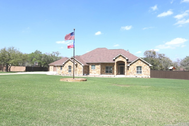 single story home with fence, stone siding, and a front lawn
