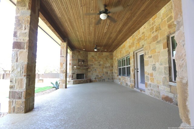 view of patio with an outdoor stone fireplace and a ceiling fan