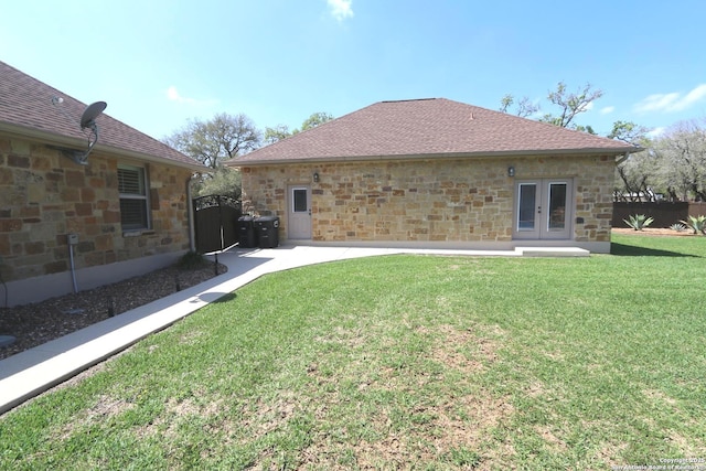 back of house with a yard, fence, french doors, and stone siding