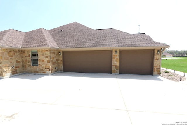 view of front of home featuring a garage, a shingled roof, concrete driveway, and stone siding