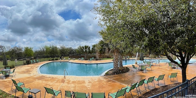 community pool with a patio area and fence