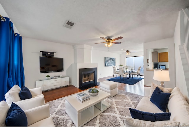9911 Alexa Pl, San Antonio, TX 78251 - living area featuring a large fireplace, a ceiling fan, dark wood-type flooring, and visible vents