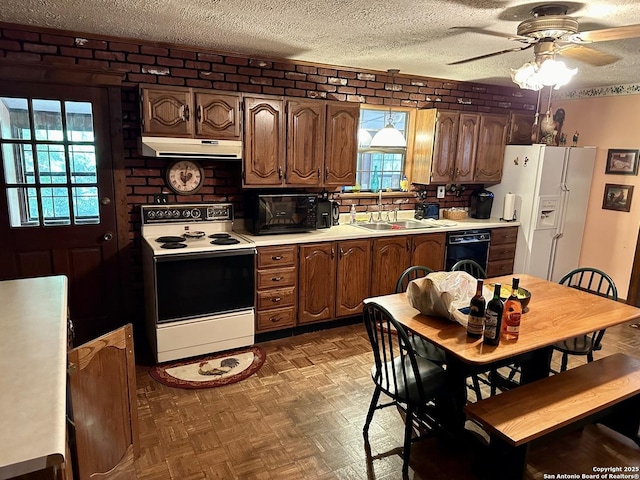 kitchen with a textured ceiling, white appliances, a ceiling fan, under cabinet range hood, and a sink