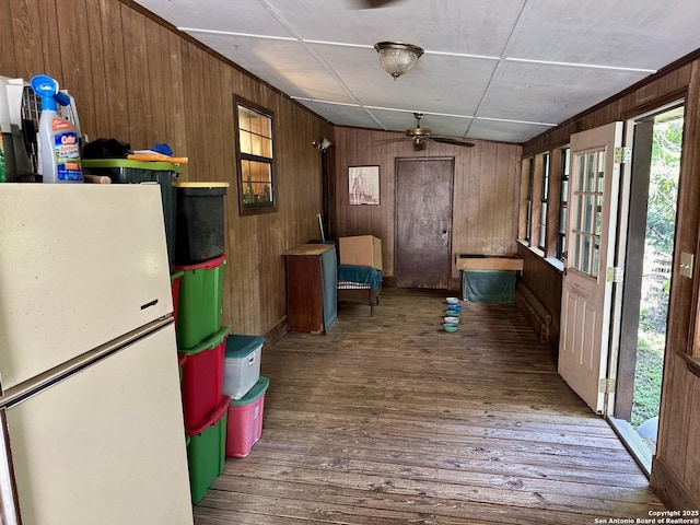 interior space with wood finished floors, a ceiling fan, and wood walls