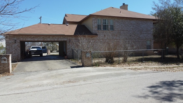 view of property exterior featuring brick siding, concrete driveway, a fenced front yard, and a chimney