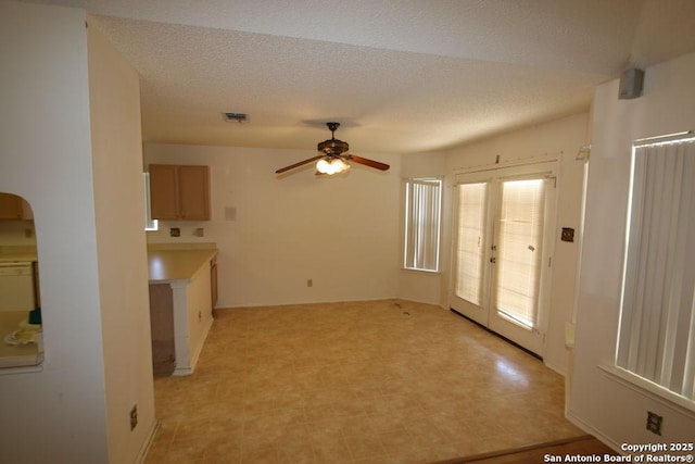 interior space with a textured ceiling, ceiling fan, visible vents, and light floors