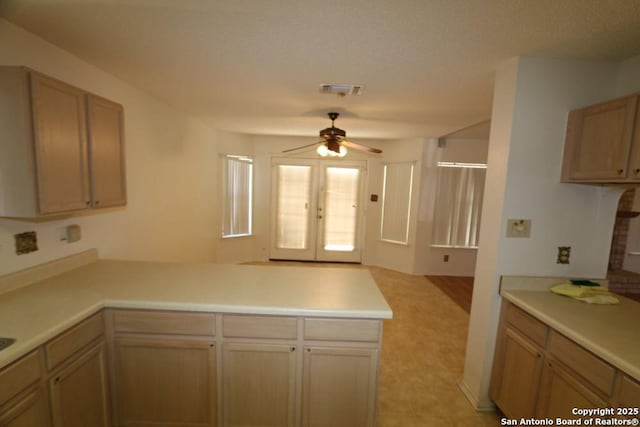 kitchen featuring visible vents, a ceiling fan, light countertops, and a peninsula