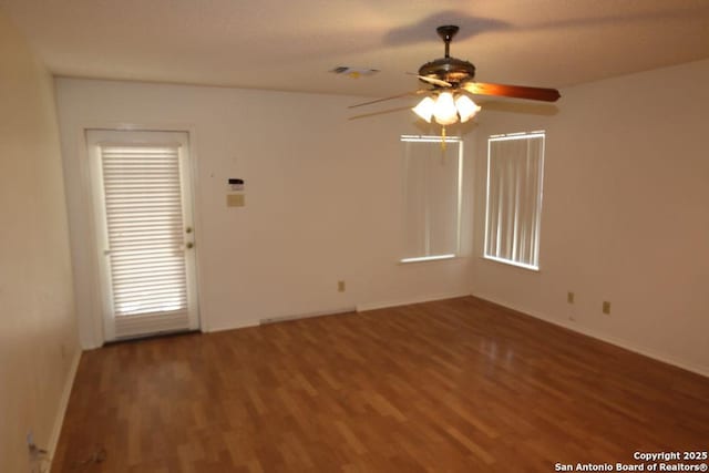 empty room with a ceiling fan, visible vents, baseboards, and wood finished floors