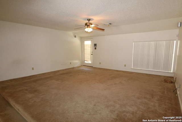 unfurnished room with a textured ceiling, ceiling fan, visible vents, and carpet