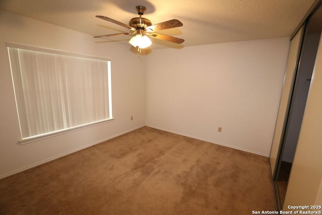 unfurnished bedroom with carpet, baseboards, a textured ceiling, a ceiling fan, and a closet