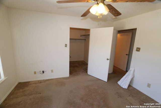 unfurnished bedroom with a closet, carpet flooring, a textured ceiling, a ceiling fan, and a walk in closet