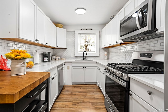 314 Trail, San Antonio, TX 78212 - kitchen featuring a sink, white cabinetry, light wood-style flooring, stainless steel appliances, and decorative backsplash