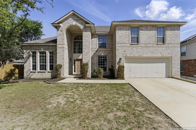 traditional-style home featuring a garage, fence, a front lawn, brick siding, and driveway