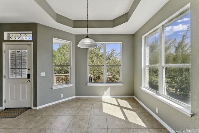 unfurnished dining area featuring tile patterned flooring, baseboards, and a raised ceiling