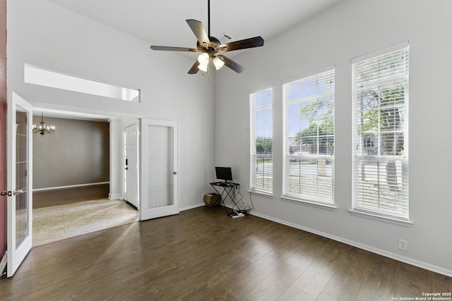 unfurnished room with french doors, wood finished floors, baseboards, and ceiling fan with notable chandelier