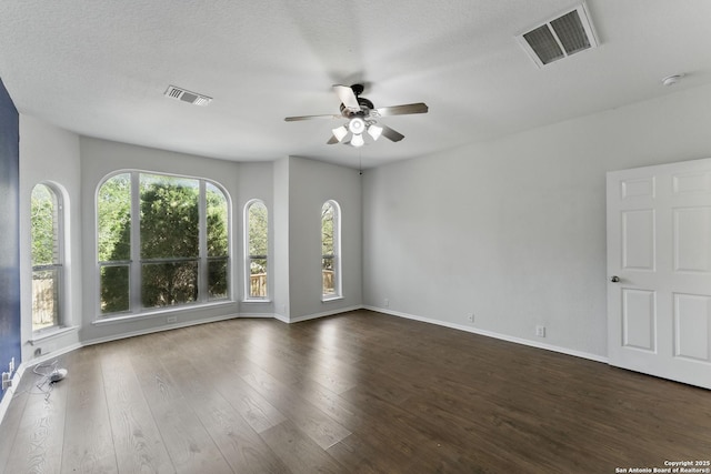spare room with dark wood finished floors, visible vents, baseboards, and ceiling fan
