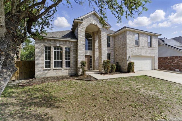 view of front of property featuring a garage, fence, concrete driveway, brick siding, and a front lawn