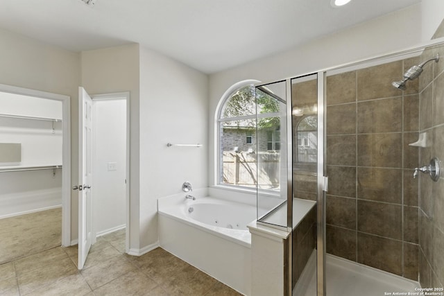 full bath with a spacious closet, tile patterned floors, a shower stall, and a jetted tub